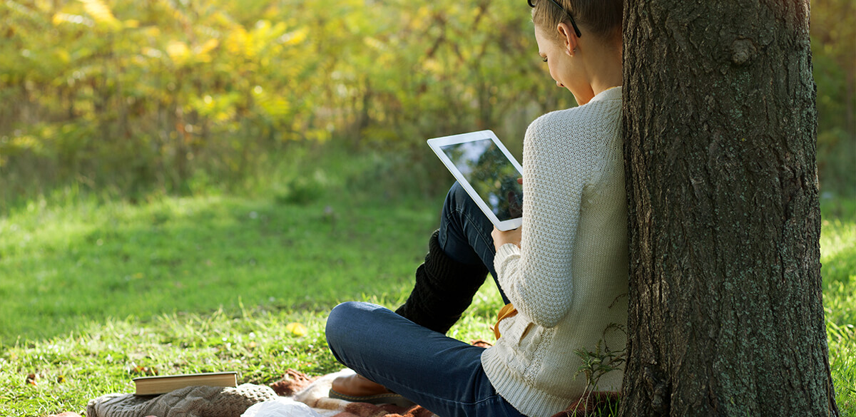 Women reading iPad outdoors
